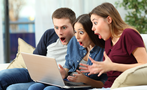 group of adults looking surprised at a laptop